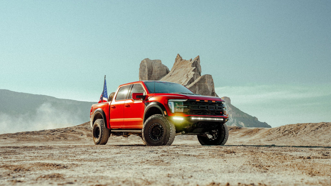 Red pickup truck on a dirt road with rock formations in the background