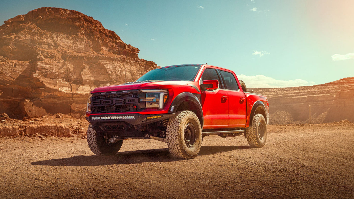 Red pickup truck on a dirt road with desert landscape